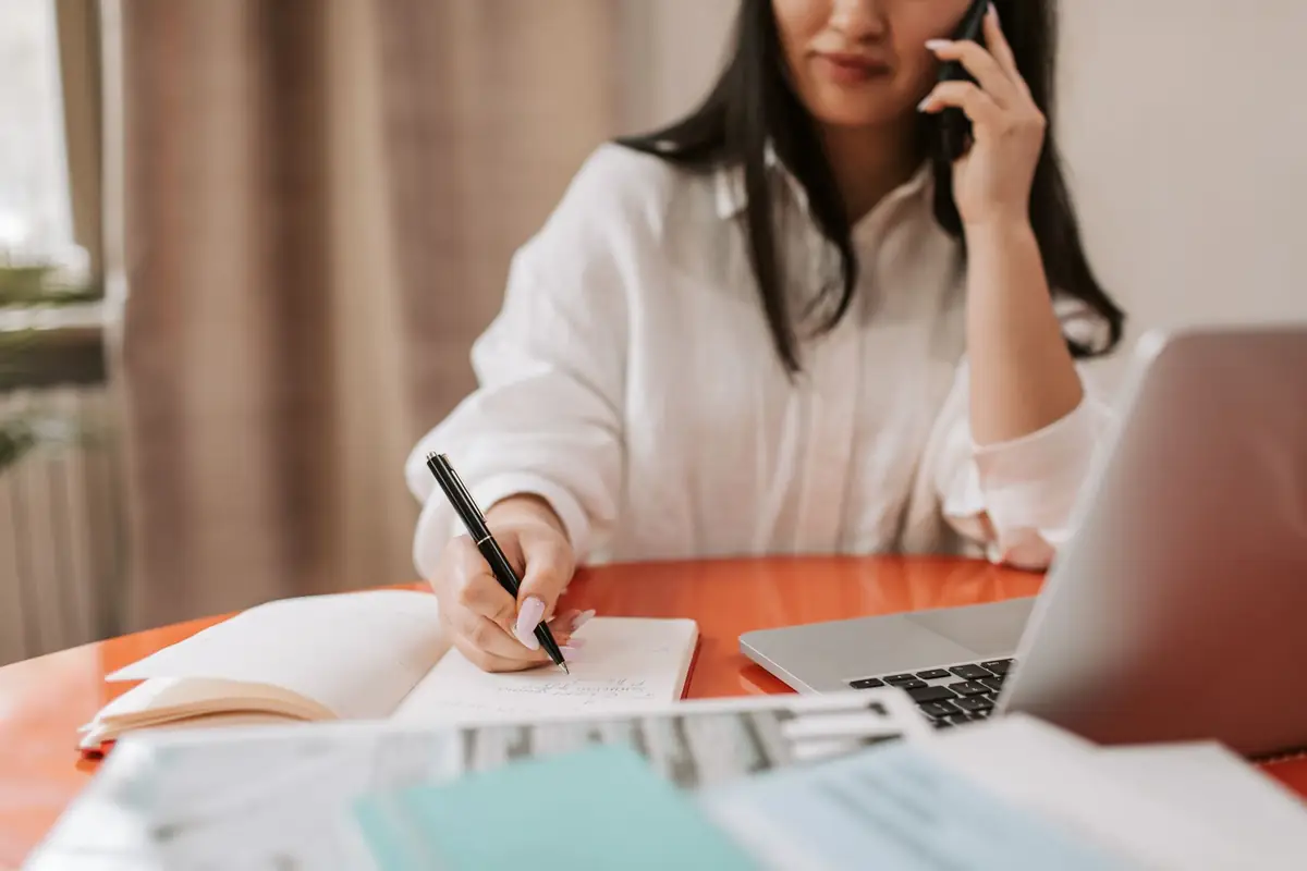 Woman on a phone call taking notes about an unpaid invoice