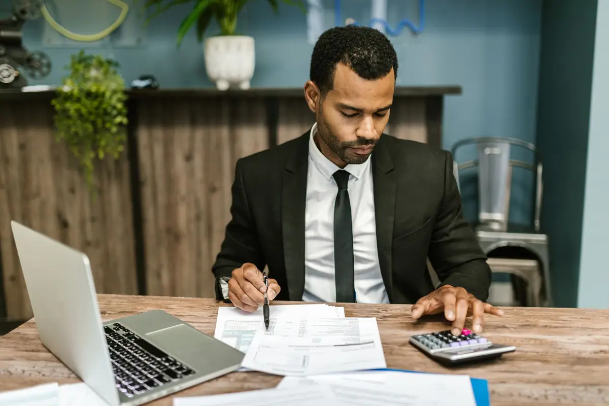 Accountant matching figures between printed statements and a laptop