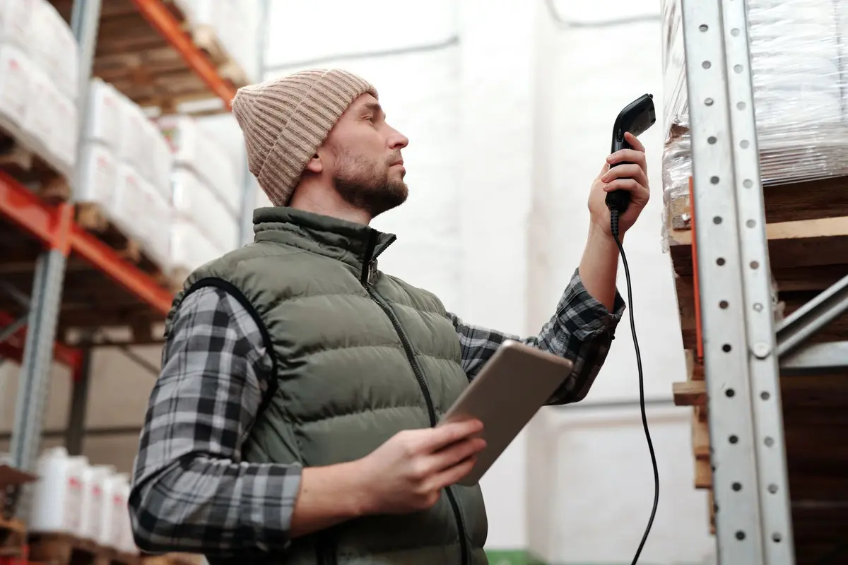 Warehouse worker checking stock with a handheld scanner and a tablet
