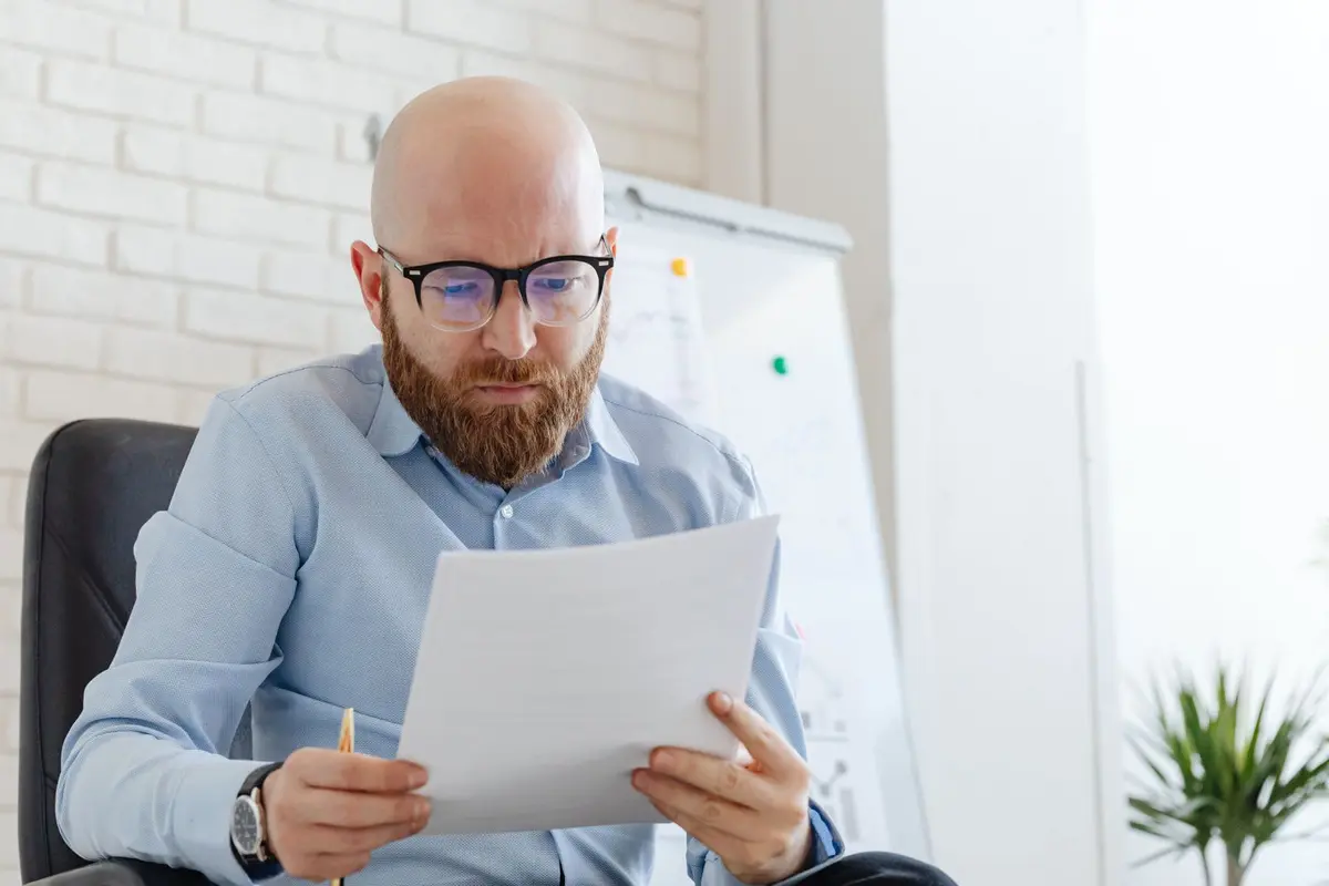 Office worker reviewing a printed document at his desk